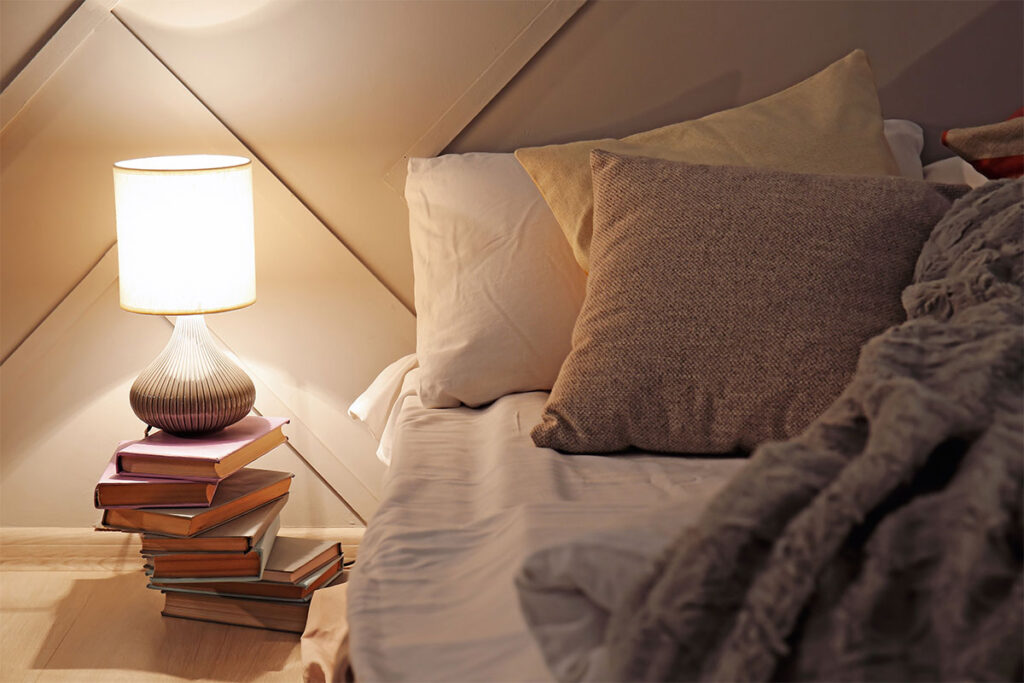 Glowing lamp with books in dark bedroom